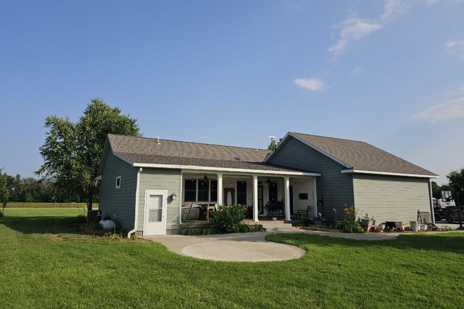Gray lap-siding ranch home with white gutters along the eaves and a white downspout at the corner, Dedicated Builders